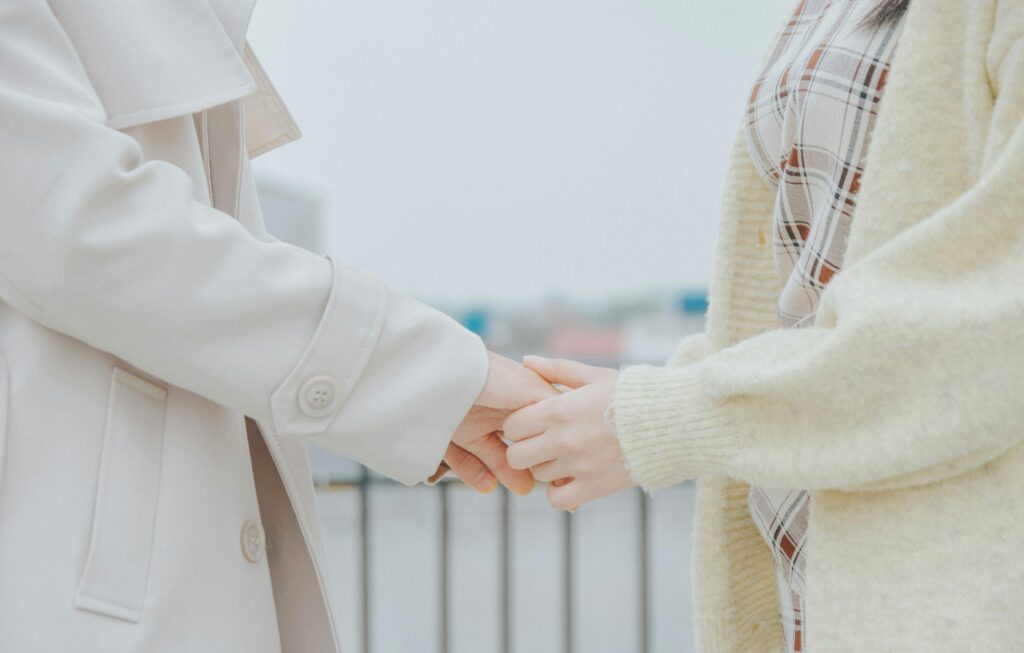 服務內容 A close-up of two people holding hands while wearing warm coats outdoors.